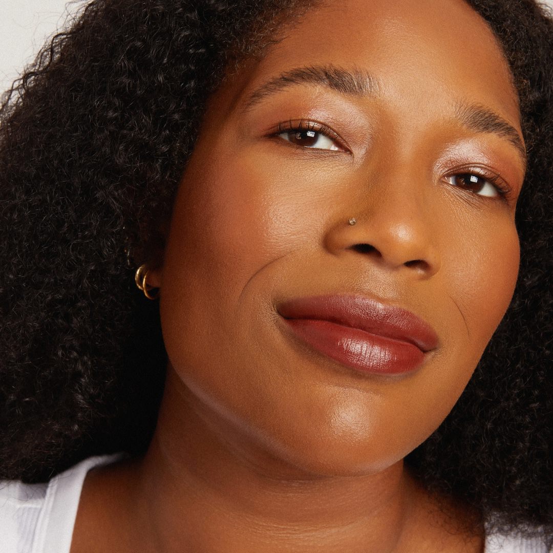 Close-up of a woman with a soft smile, wearing makeup.