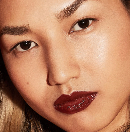 Close-up of a person wearing dark red lipstick with a blurred background