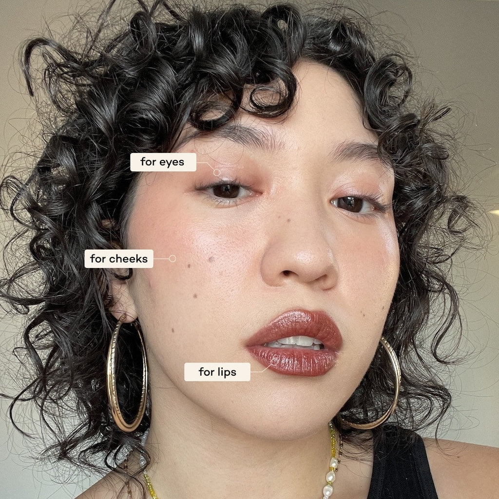 Woman with makeup labels for eyes, cheeks, and lips on a neutral background