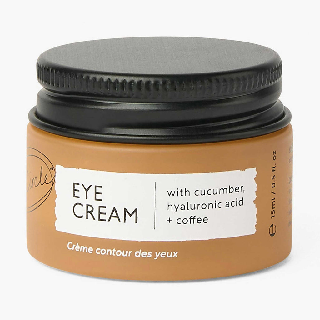 Jar of eye cream with cucumber, hyaluronic acid, and coffee on a white background
