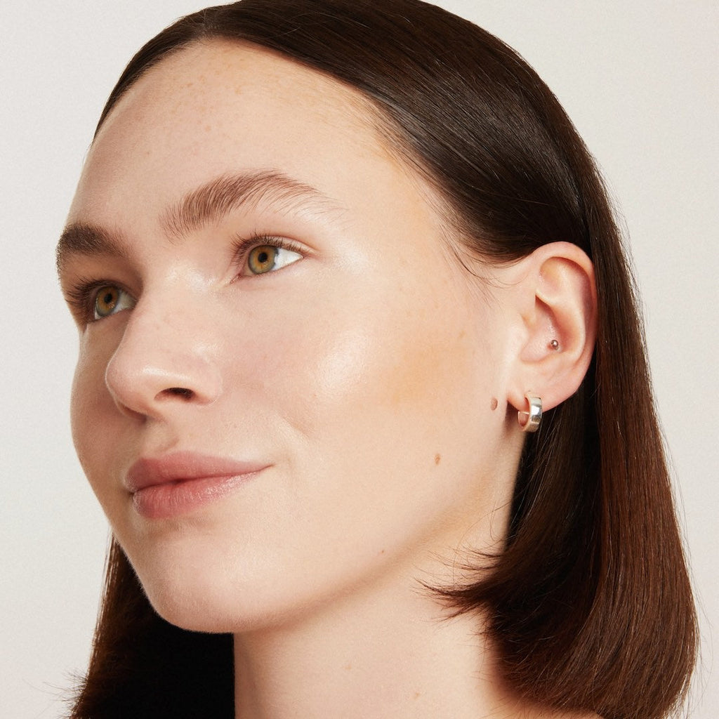 Close-up of a woman wearing foundation makeup on a plain background