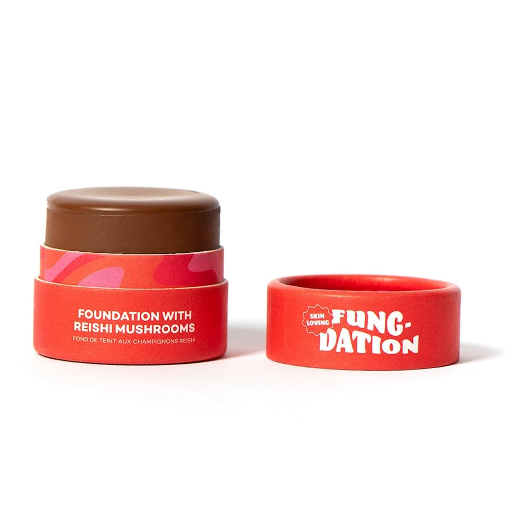 Red cosmetic pot with brown foundation and lid with 'Fung-Dation' text on a white background