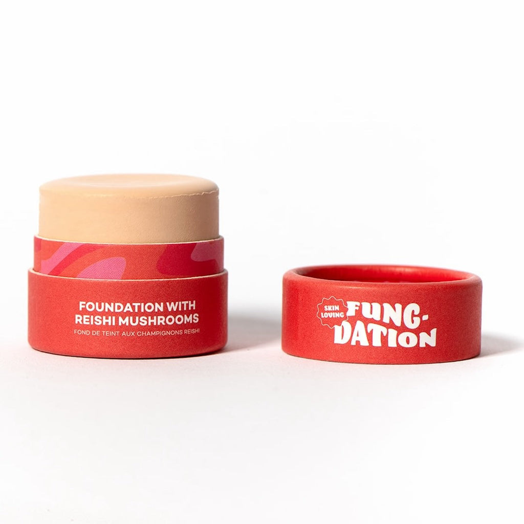 Red cosmetic pot with light beige foundatoin and red lid with 'FUNC-DATION' text on a white background