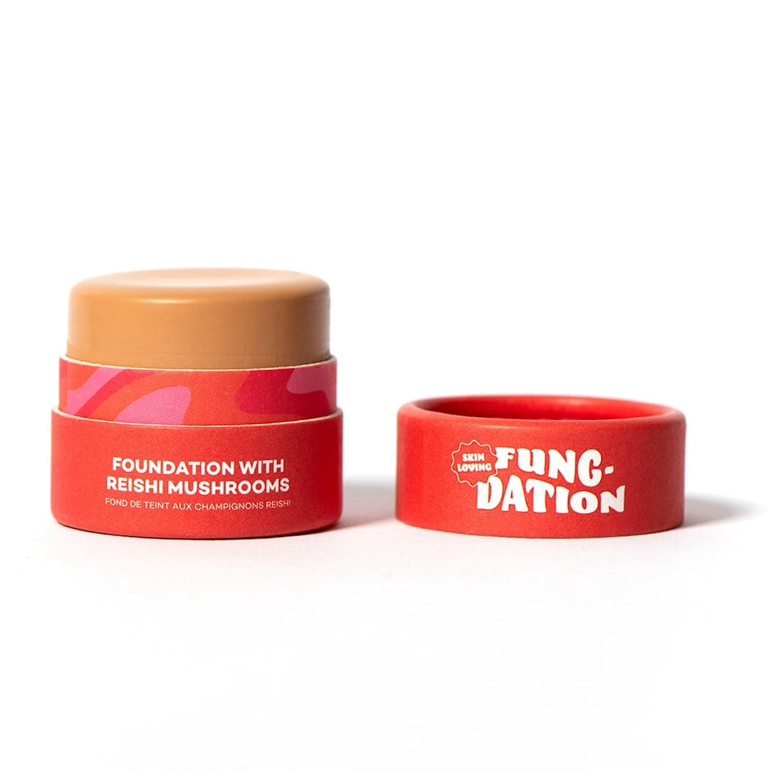 Red cosmetic pot with beige foundation on a white background