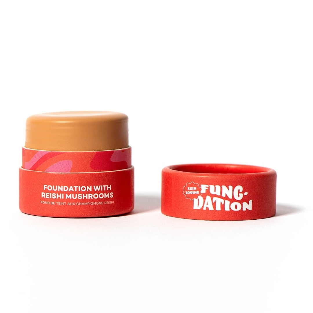 Red cosmetic pot with beige foundation on a white background