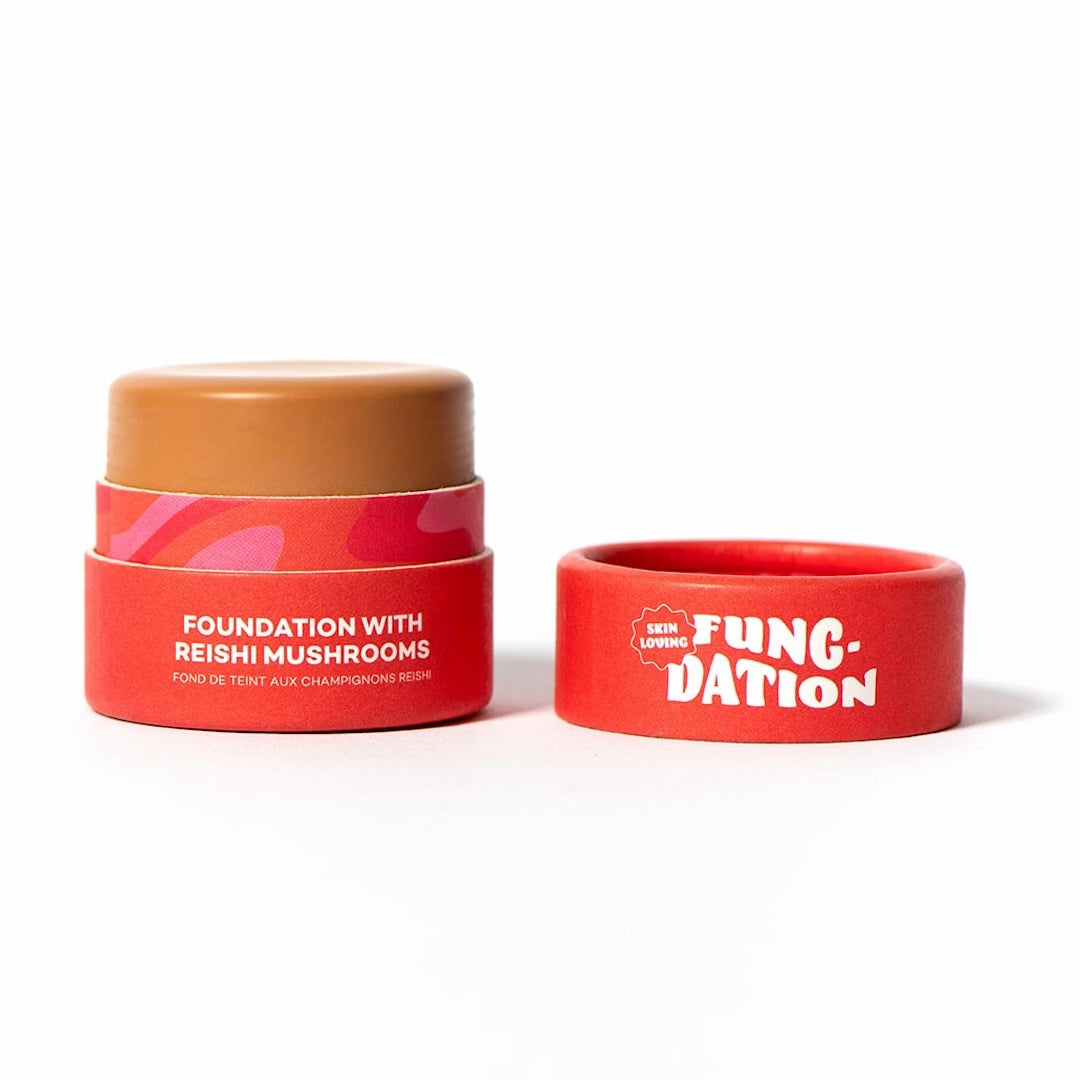 Red cosmetic pot with light brown foundation and red lid labeled 'Fung-Dation' on a white background