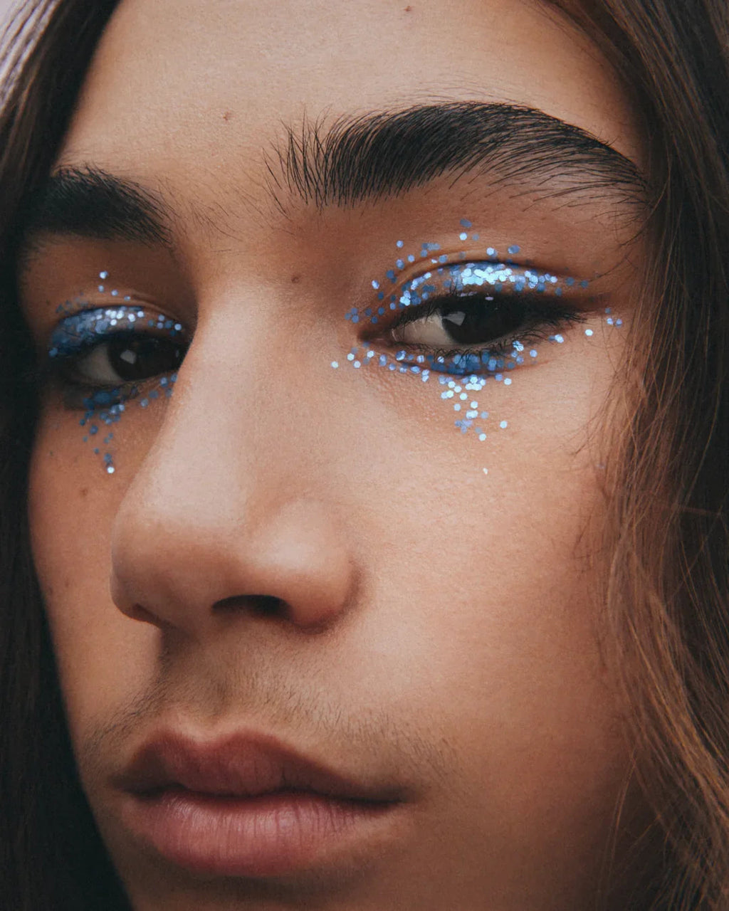 Close-up of a person with blue glittery eye makeup.