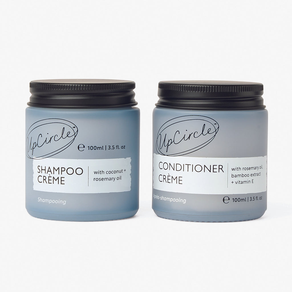 Two jars of UpCircle Shampoo Crème and Conditioner Crème on a white background