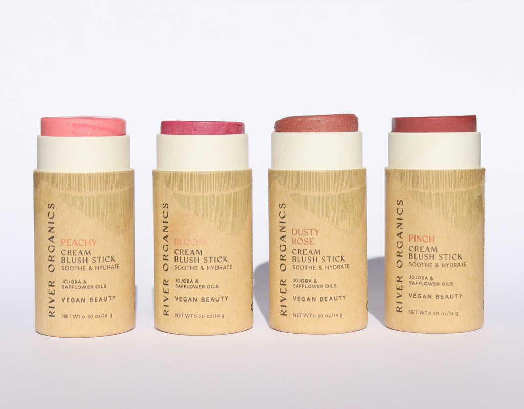 Four cream blush sticks from River Organics on a light gray background