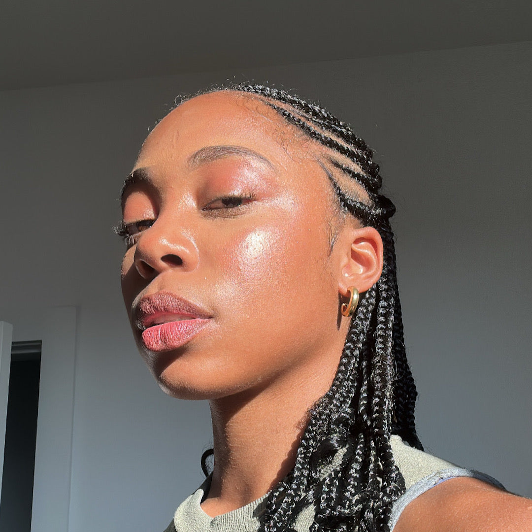 Woman with braided hair looking to the side against a neutral background