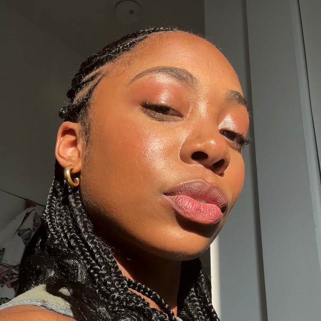 Woman with braided hair and pink lipstick against a neutral background