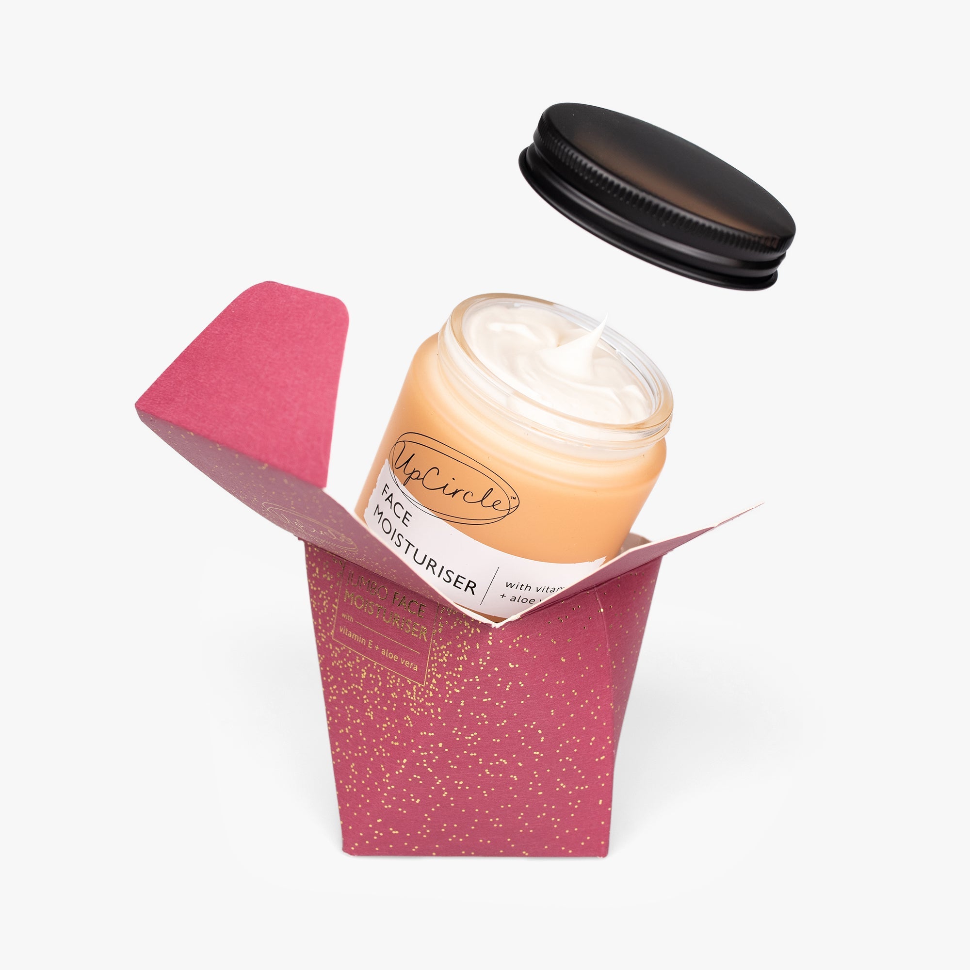 Jar of face moisturiser in a pink box with a black lid on a white background
