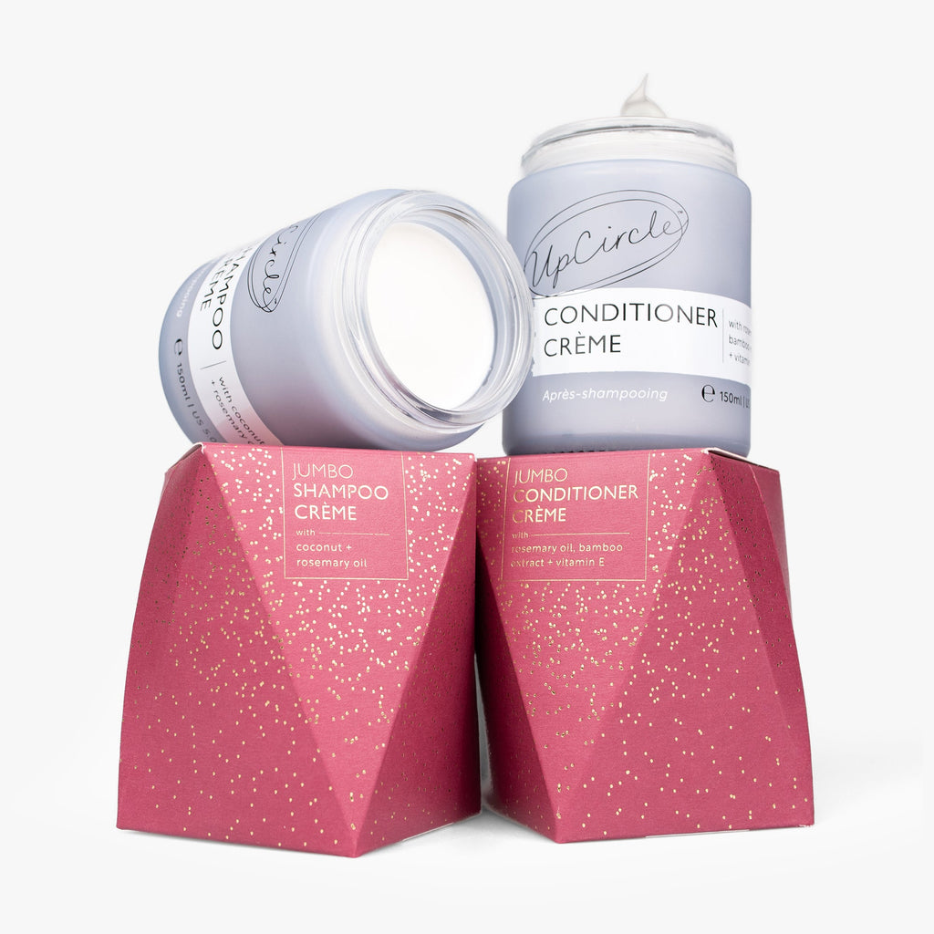 Two jars of UpCircle Shampoo and Conditioner Creme with pink boxes on a white background
