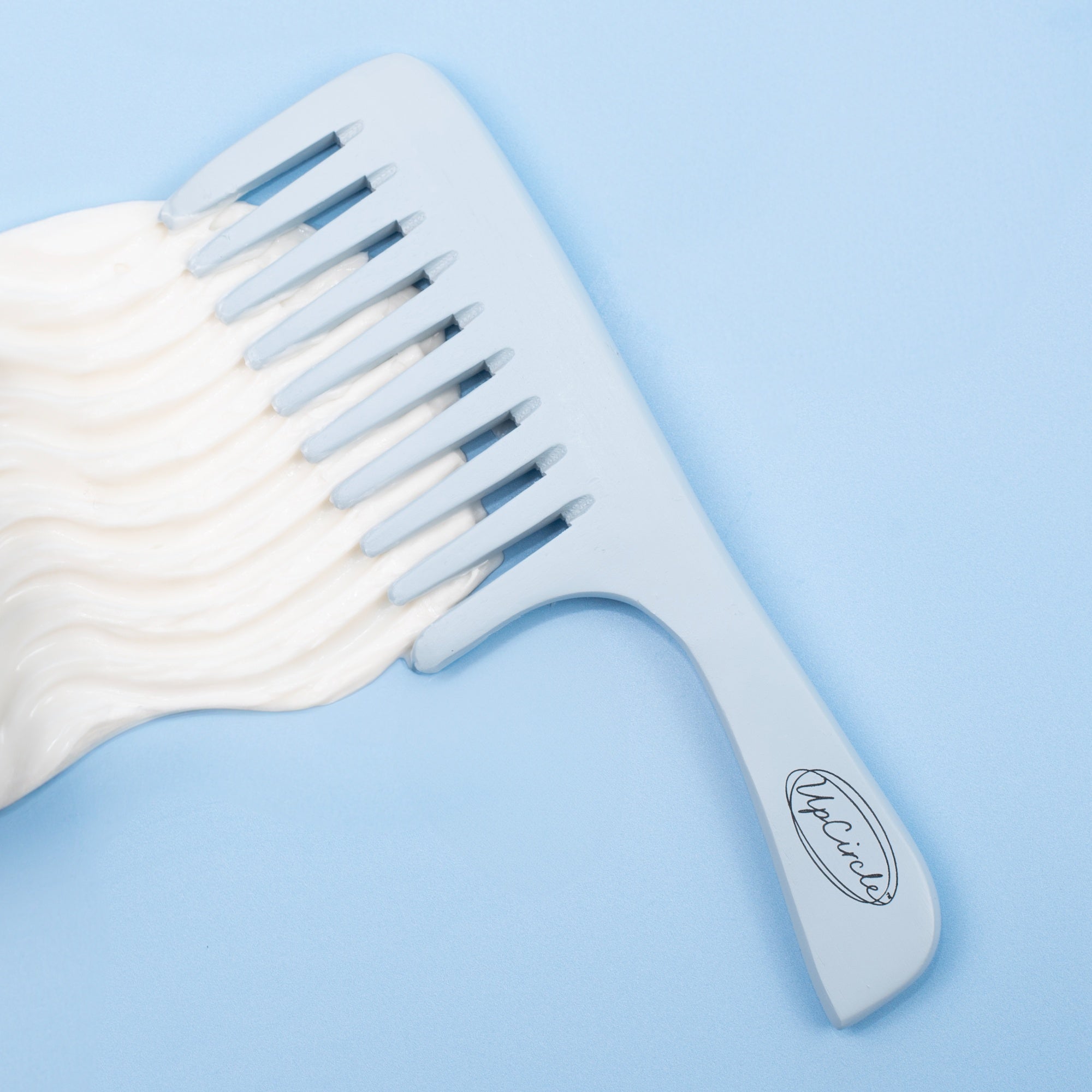 White wide-tooth comb on a light blue background