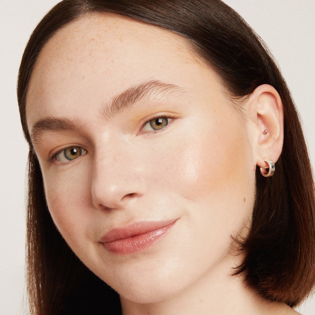 Close-up of a woman's face wearing foundation makeup with a neutral background