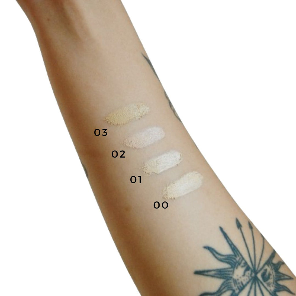 Swatches of different makeup shades on a person's arm with visible tattoo