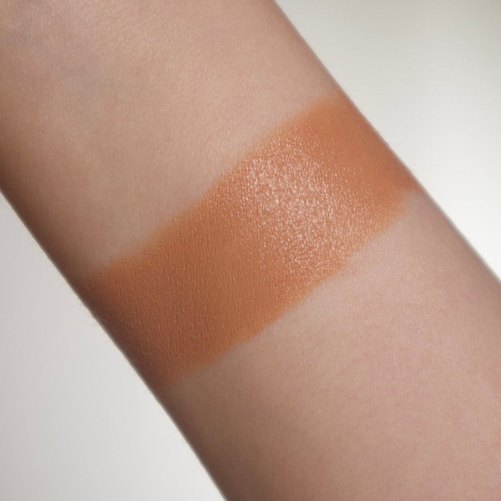 Close-up of a wrist with makeup swatch on a light background