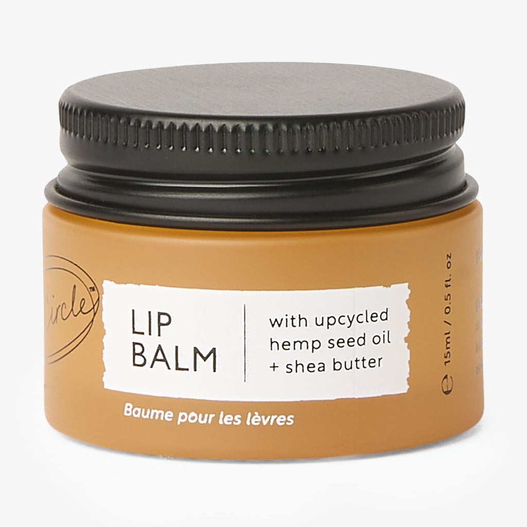 Lip balm jar with black lid and brown body on a white background