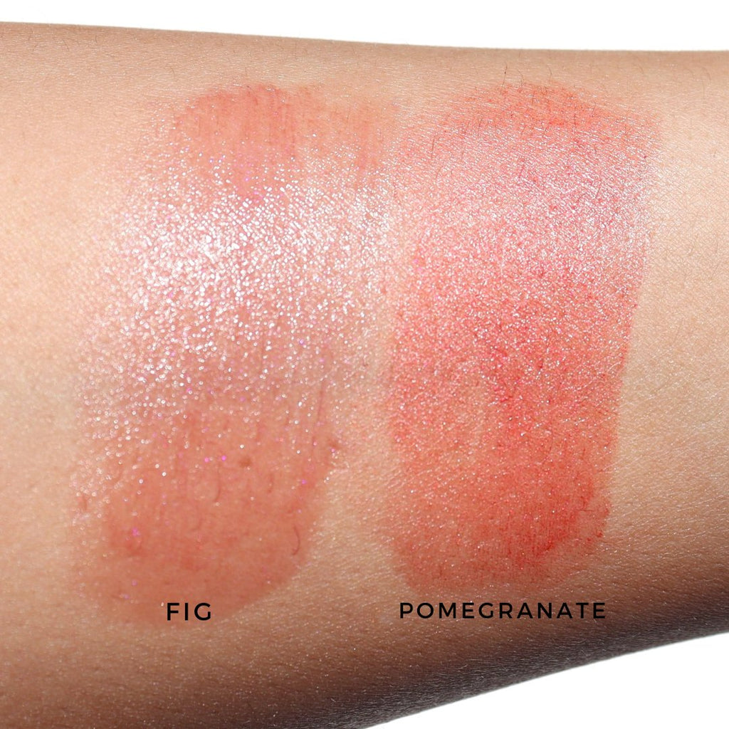 Lip stain swatches labeled 'Fig' and 'Pomegranate' on a person's arm.