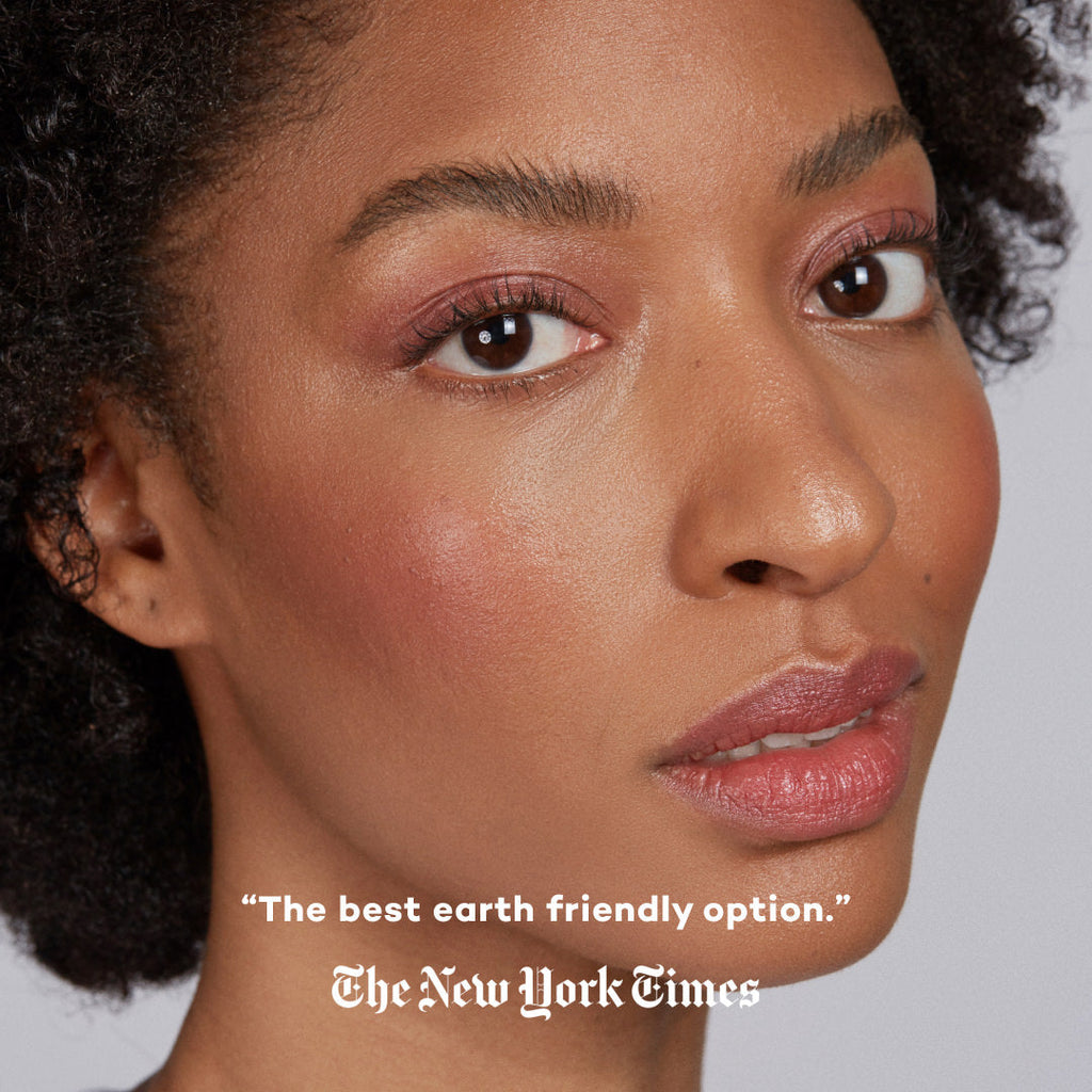 Close-up of a woman's face with plum makeup and a quote from The New York Times on a gray background