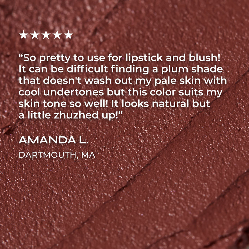 Close-up of a plum-colored makeup product with a customer review on a matching background