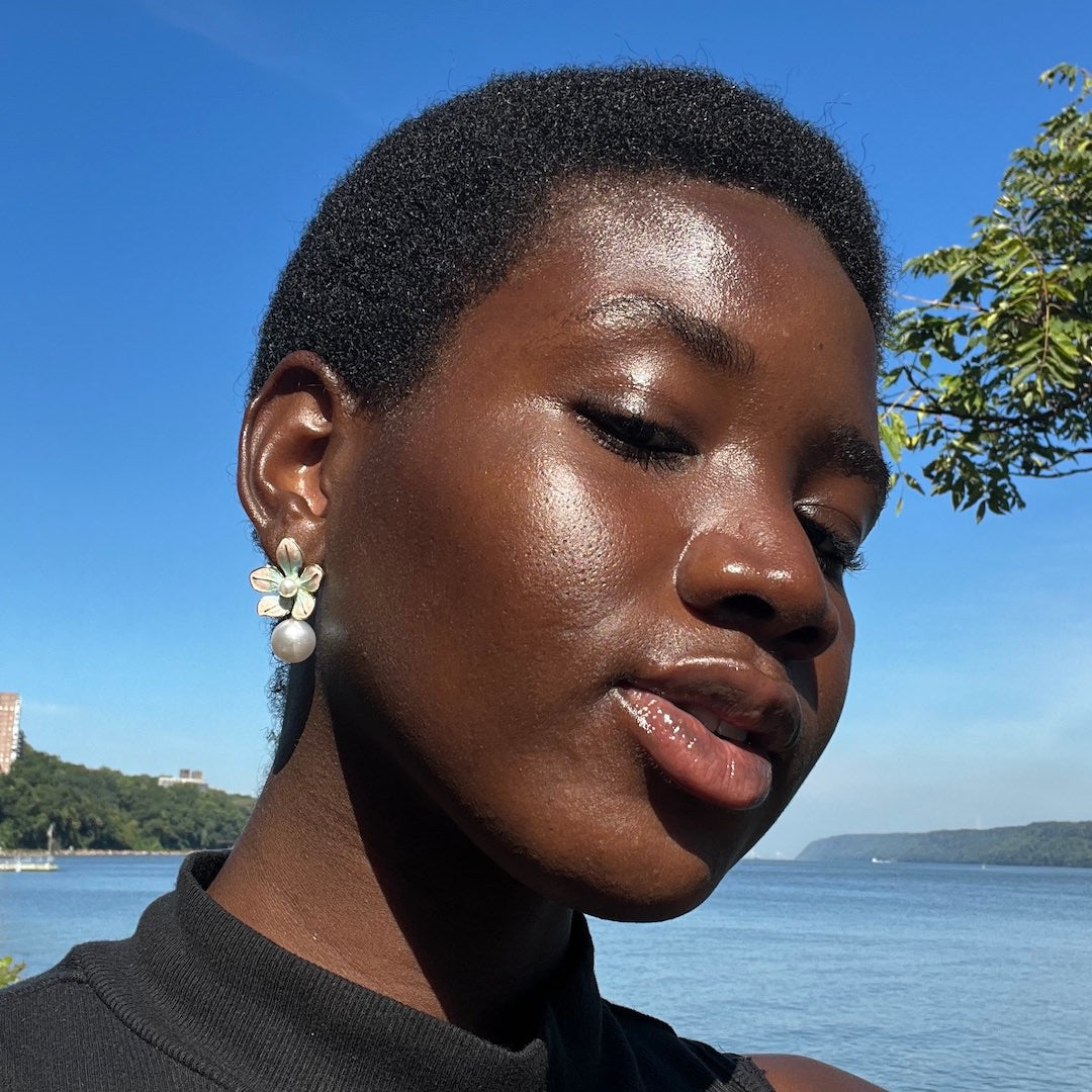 Woman with short hair and earrings against a blue sky and water background