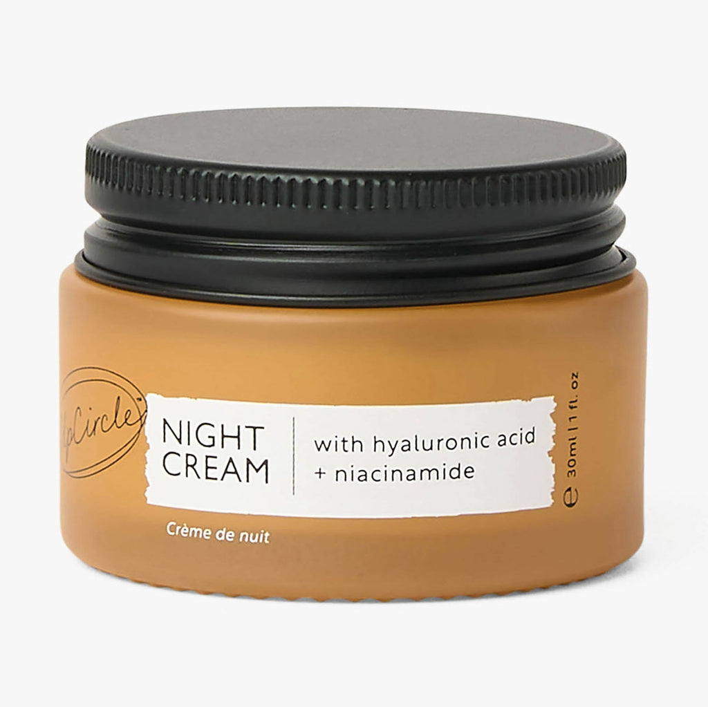 Jar of night cream with black lid on a white background