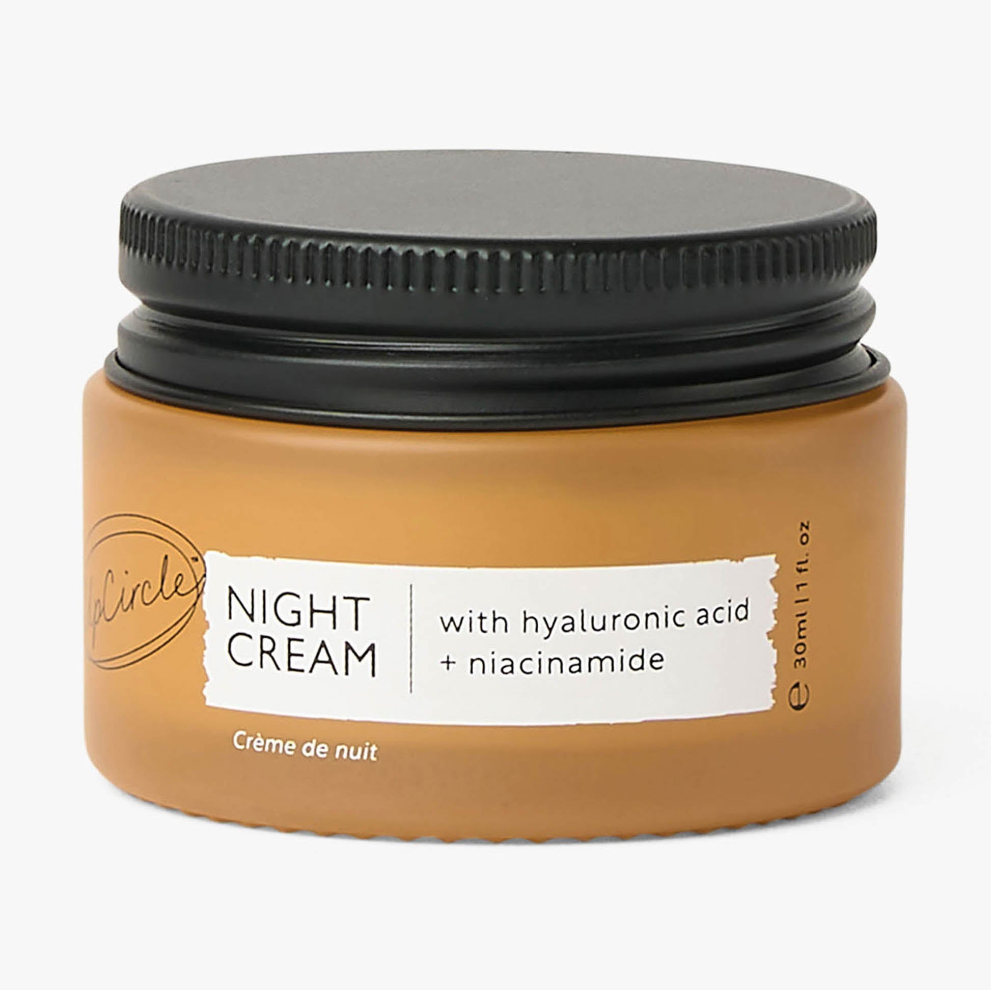 Jar of night cream with black lid on a white background