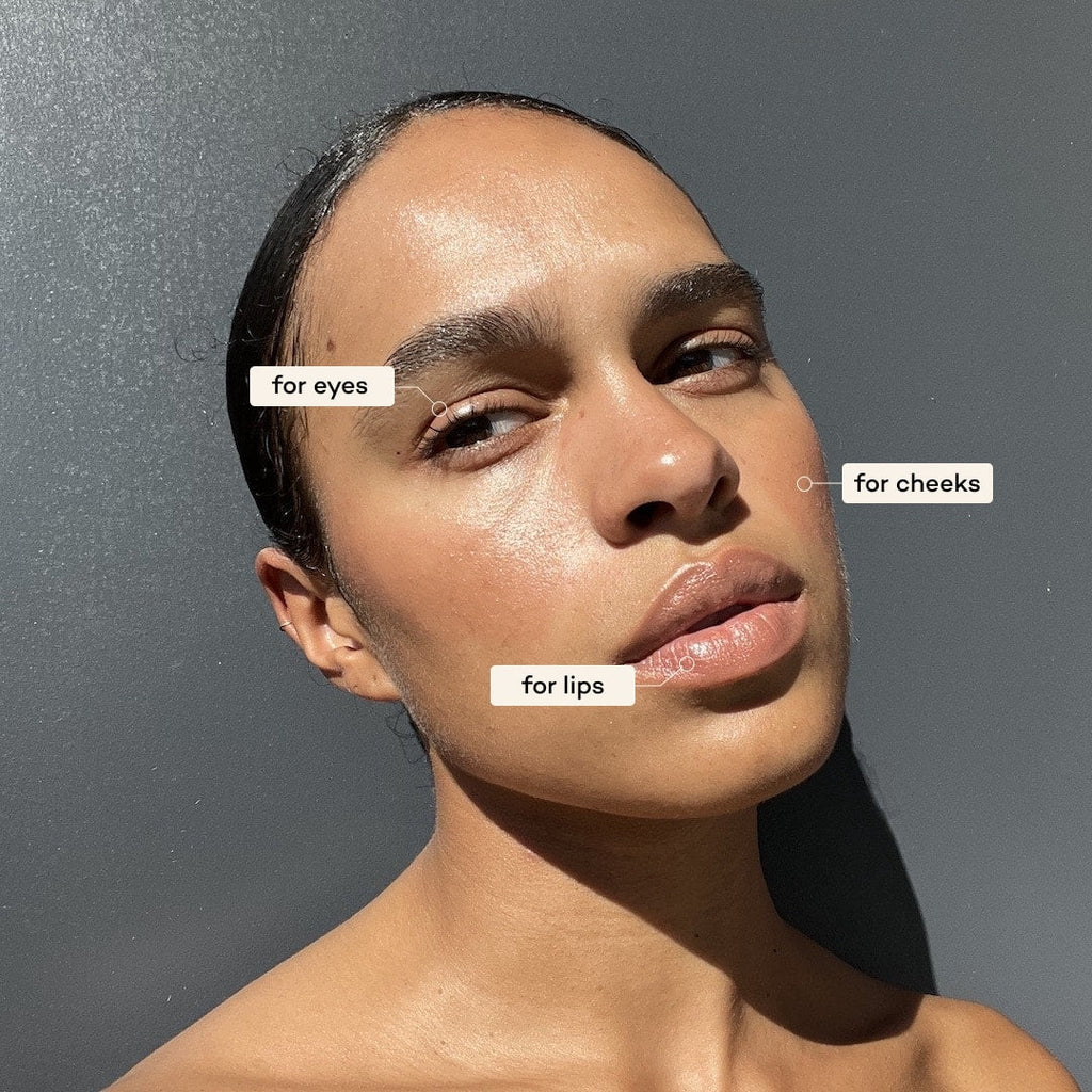 Woman applying makeup with labels for eyes, cheeks, and lips on a gray background