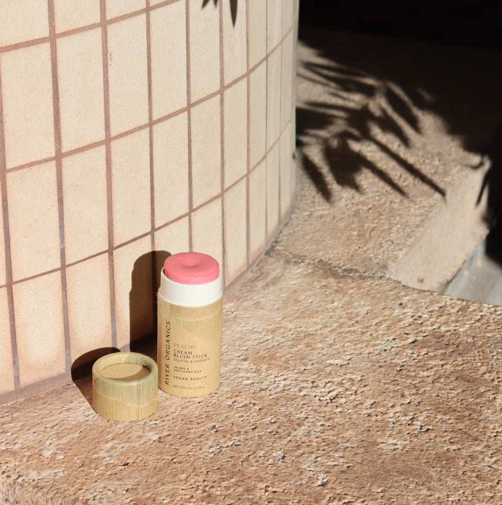 Blush stick with paper cap on a textured surface next to a tiled wall