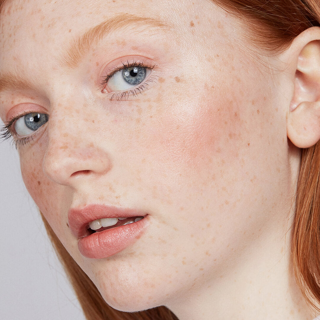 Close-up of a person with freckles and makeup on their face