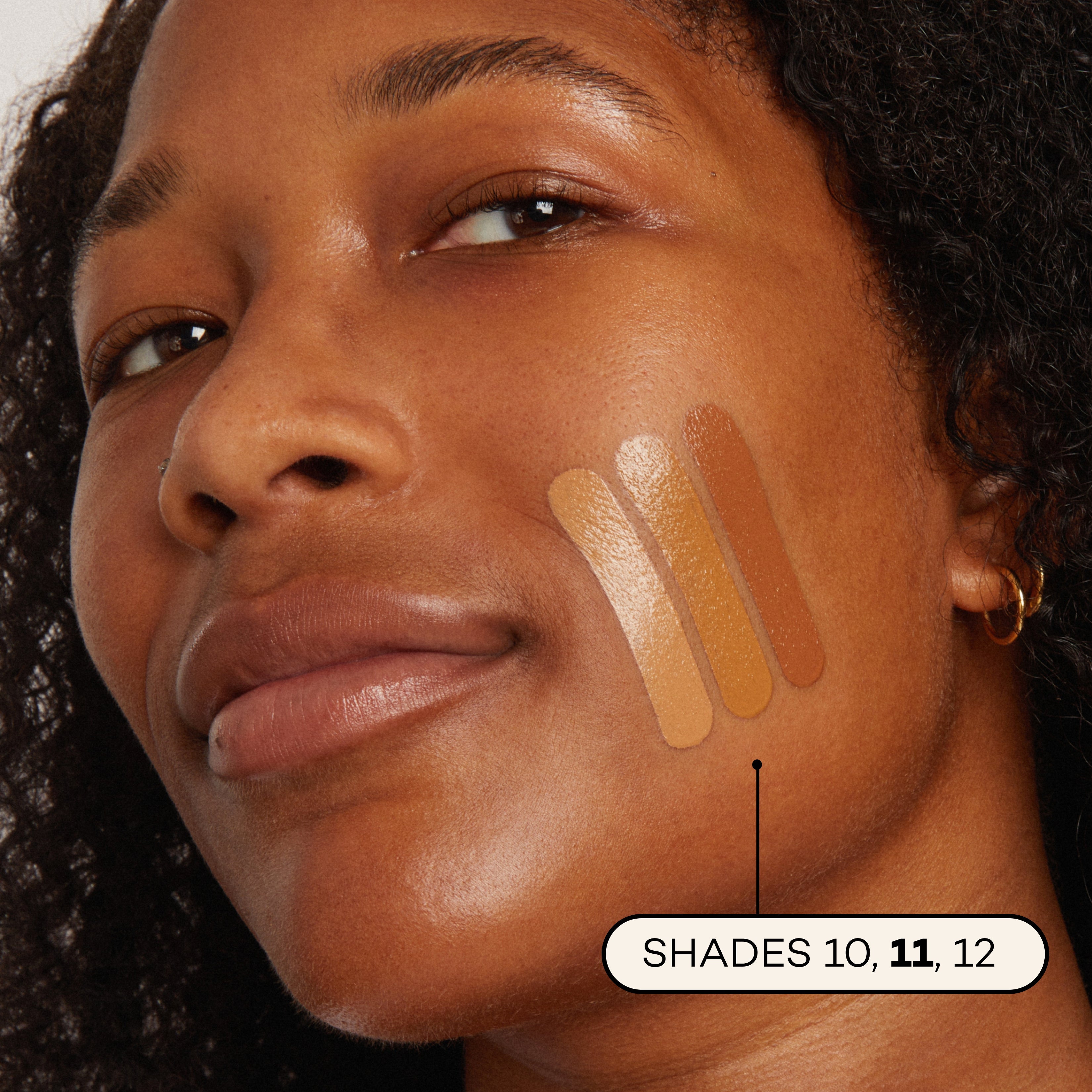 Close-up of a woman's face with foundation swatches on her cheek, labeled with shades 10, 11, and 12.