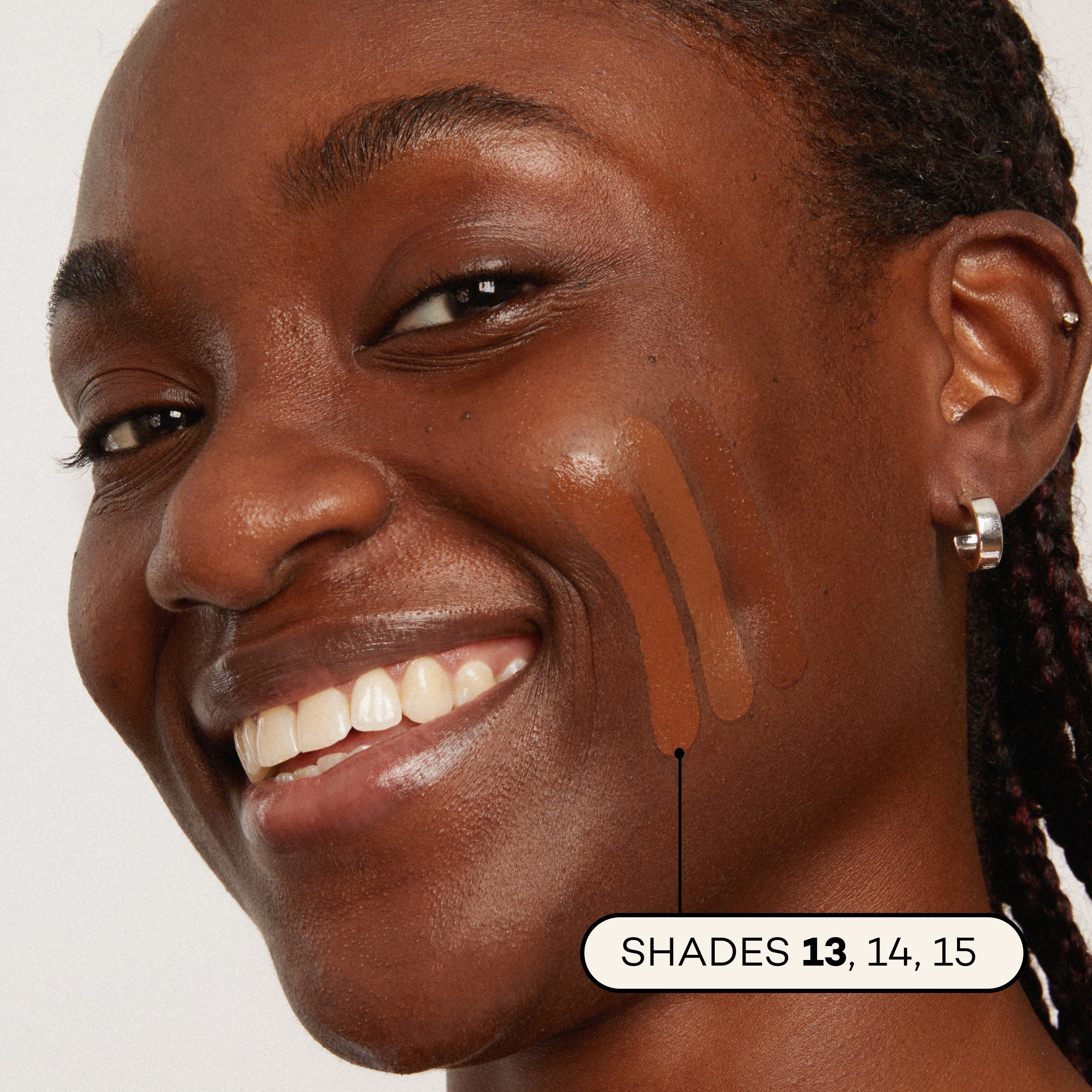 Woman with brown skin showing foundation swatches on face, labeled with shades 13, 14, 15.
