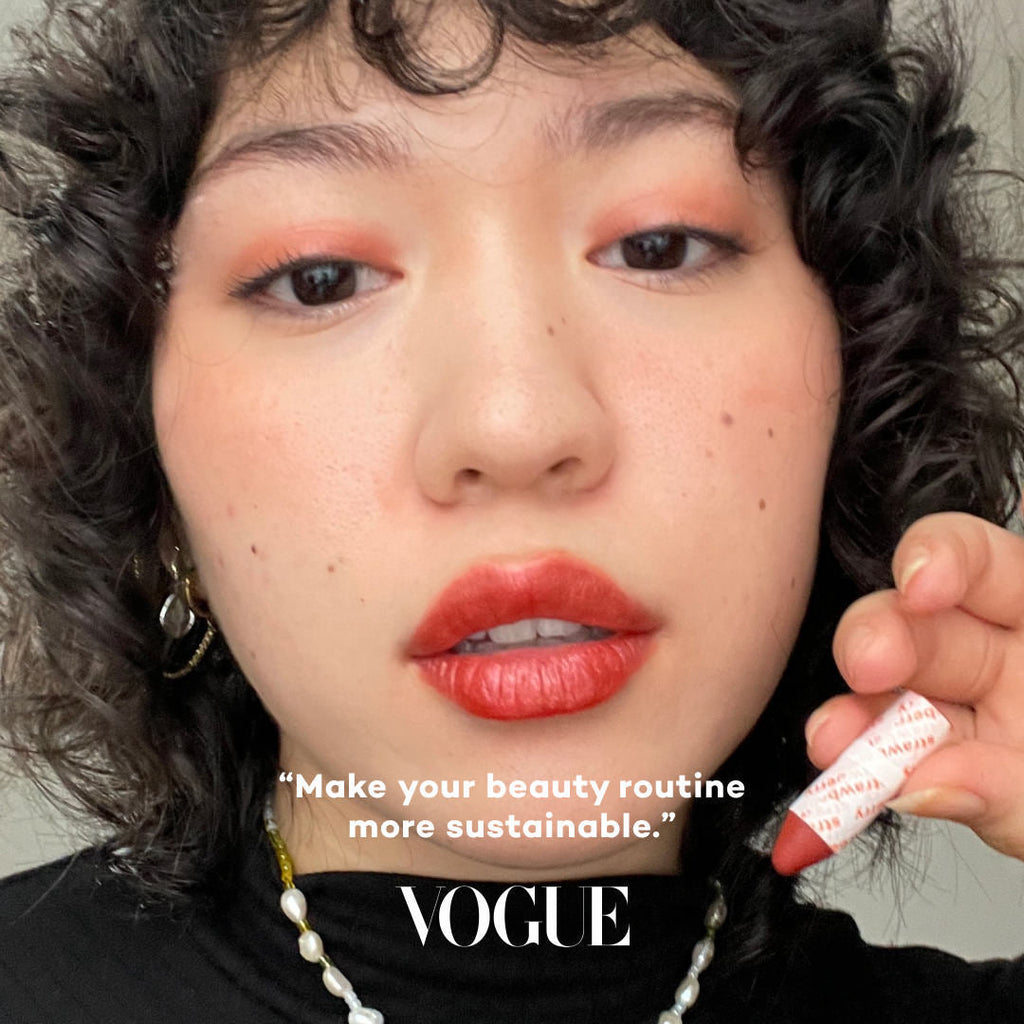 Person holding a lipstick with 'Vogue' text overlay and sustainability message.