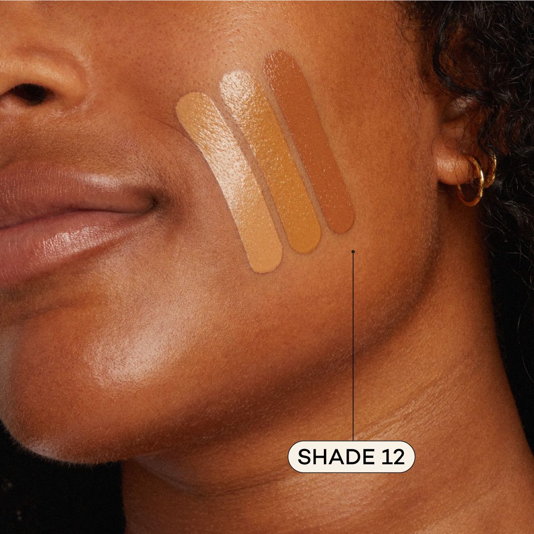 Close-up of a woman's face with foundation samples applied to her cheek, labeled 'Shade 12'.