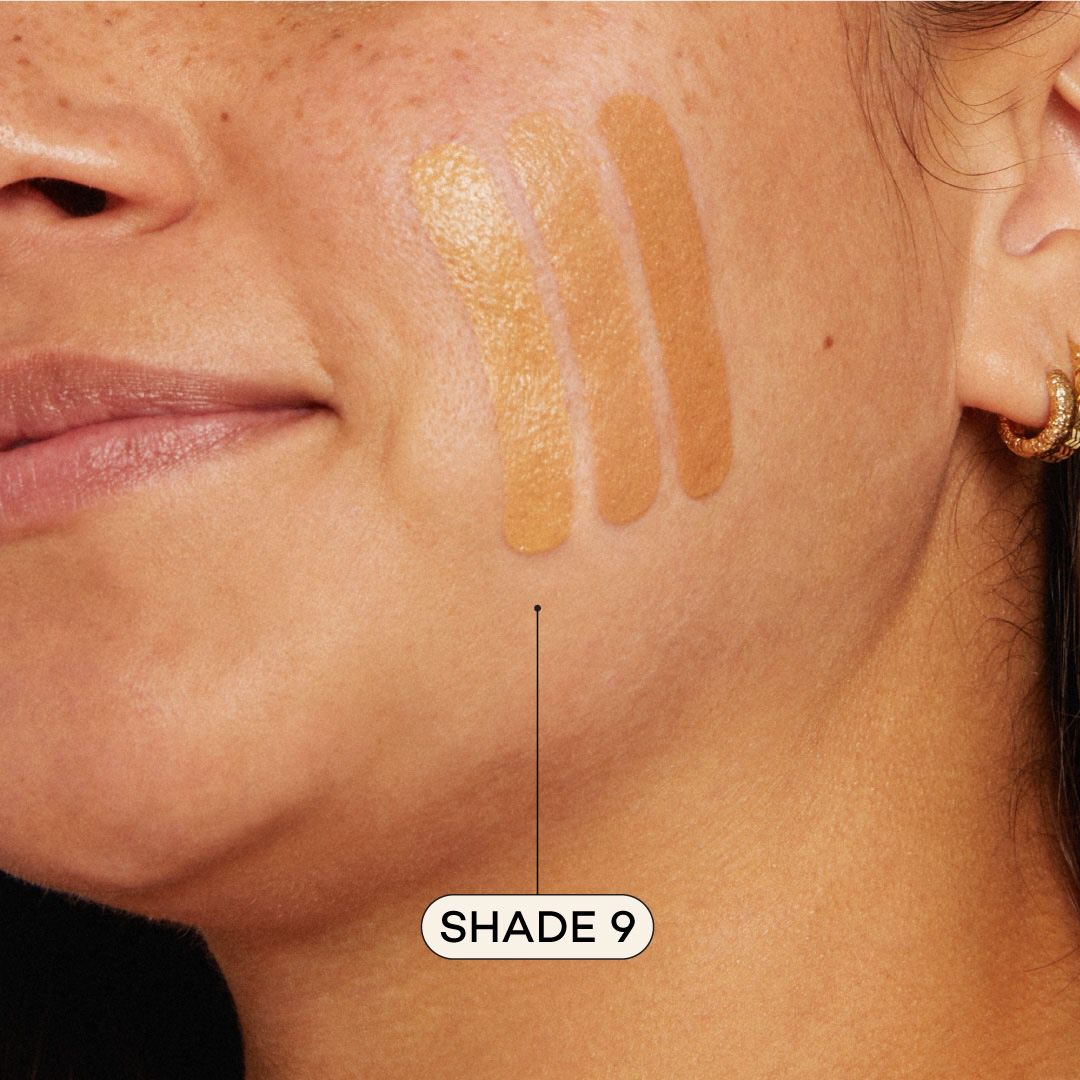 Close-up of a woman's face with foundation swatches on her cheek, labeled 'Shade 9'.