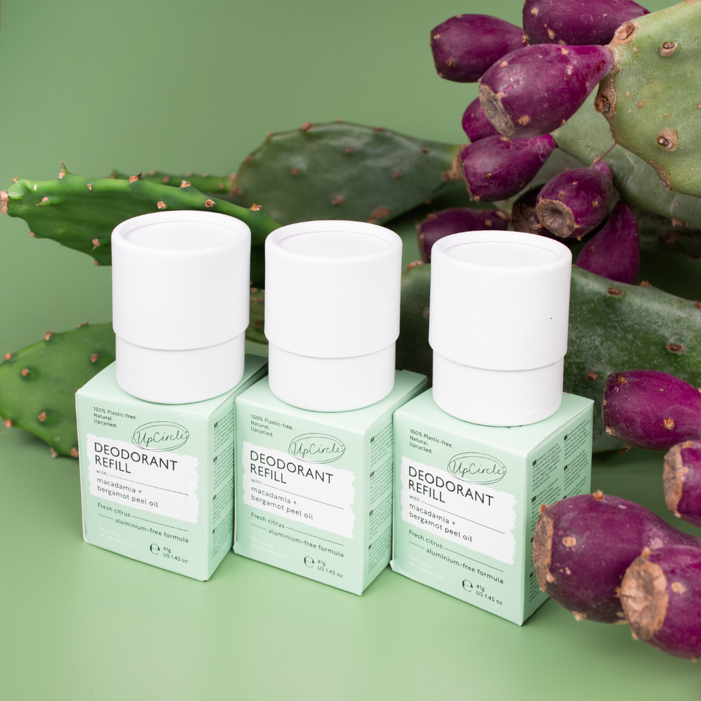 Three deodorant refills with green boxes on a green background with cactus.