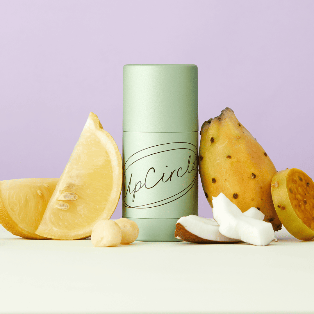 Green cylindrical container labeled 'UpCircle' with a sliced lemon and prickly pear cactus on a light purple background.