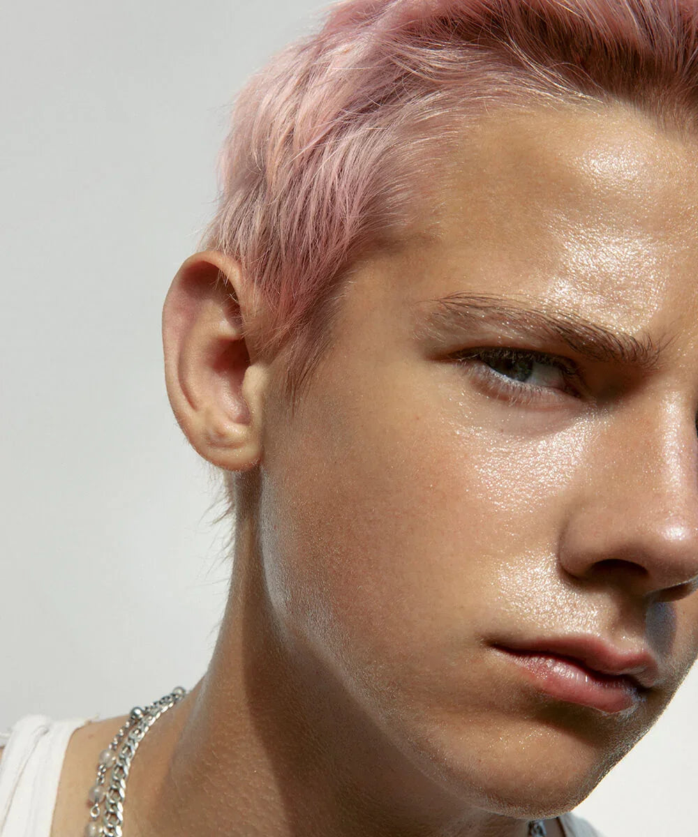Close-up of a person with pink hair with focus on glossy skin texture against a light background