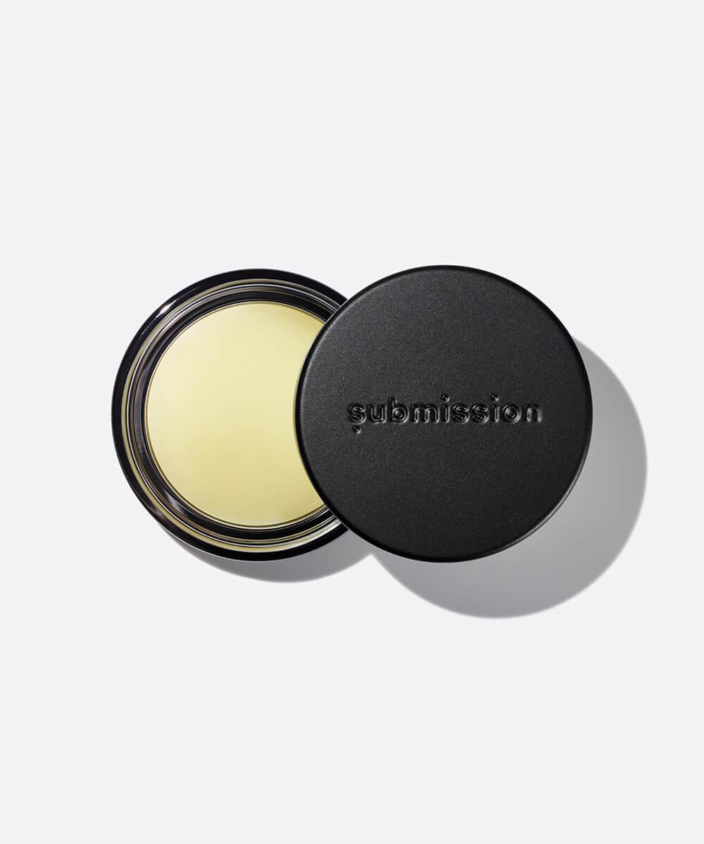 Cosmetic balm with 'submission' branding on a light gray background