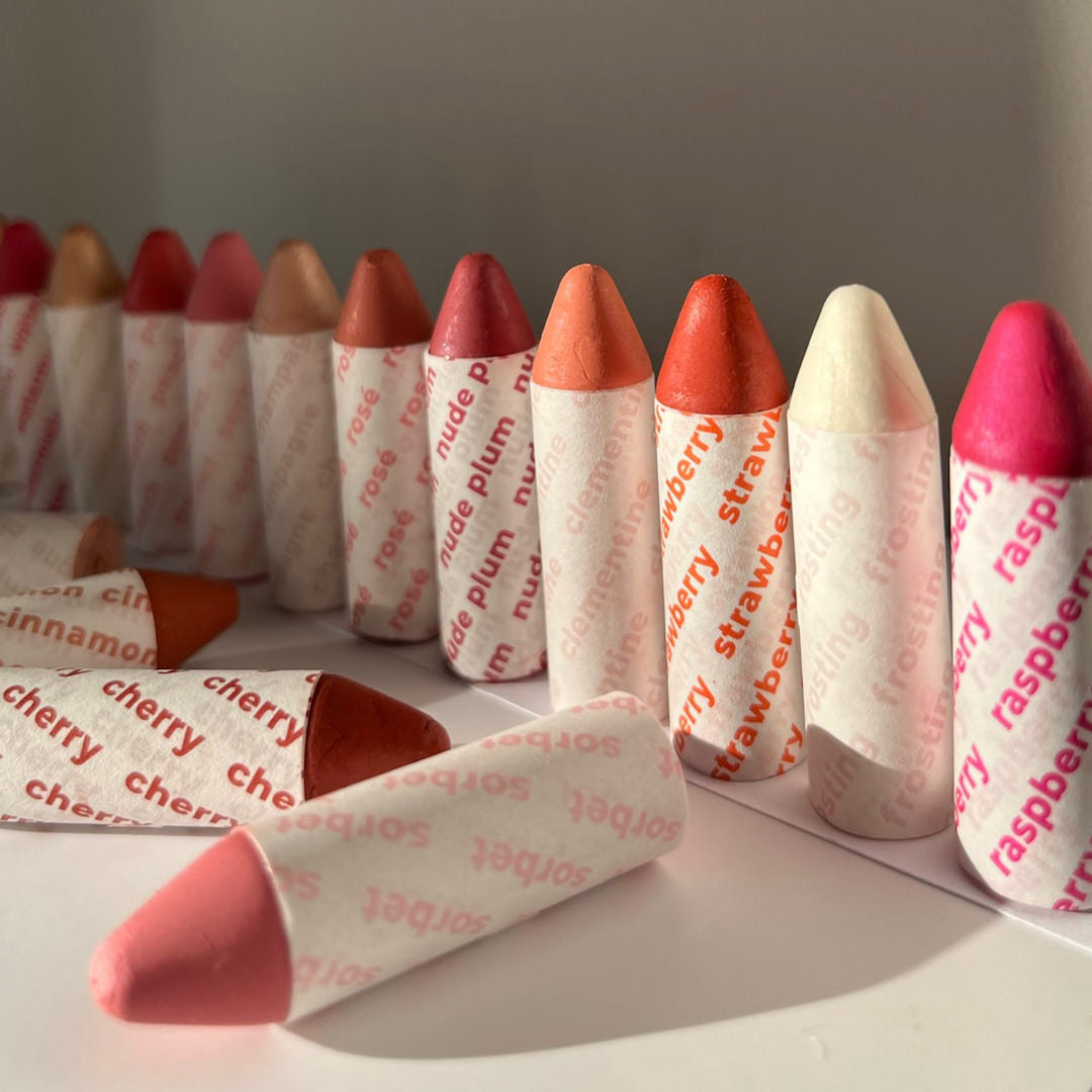 Assorted lip crayons with visible color names on a white surface.