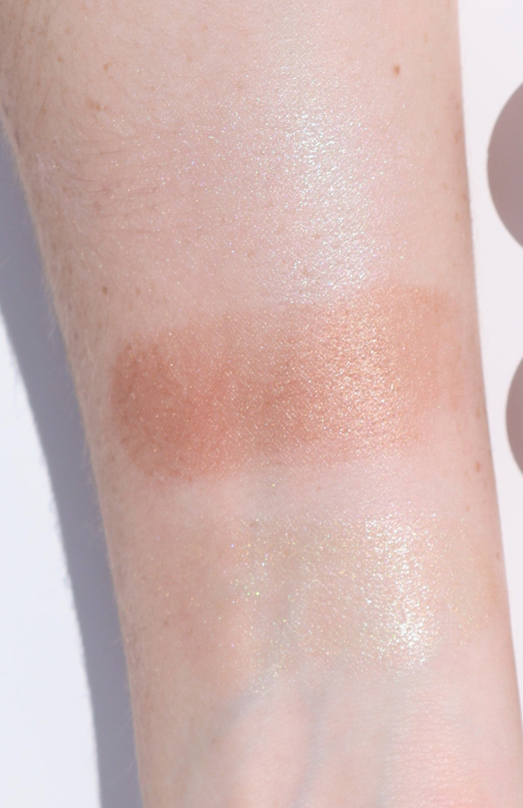 Close-up of a swatch of bronzer on a person's arm with a neutral background