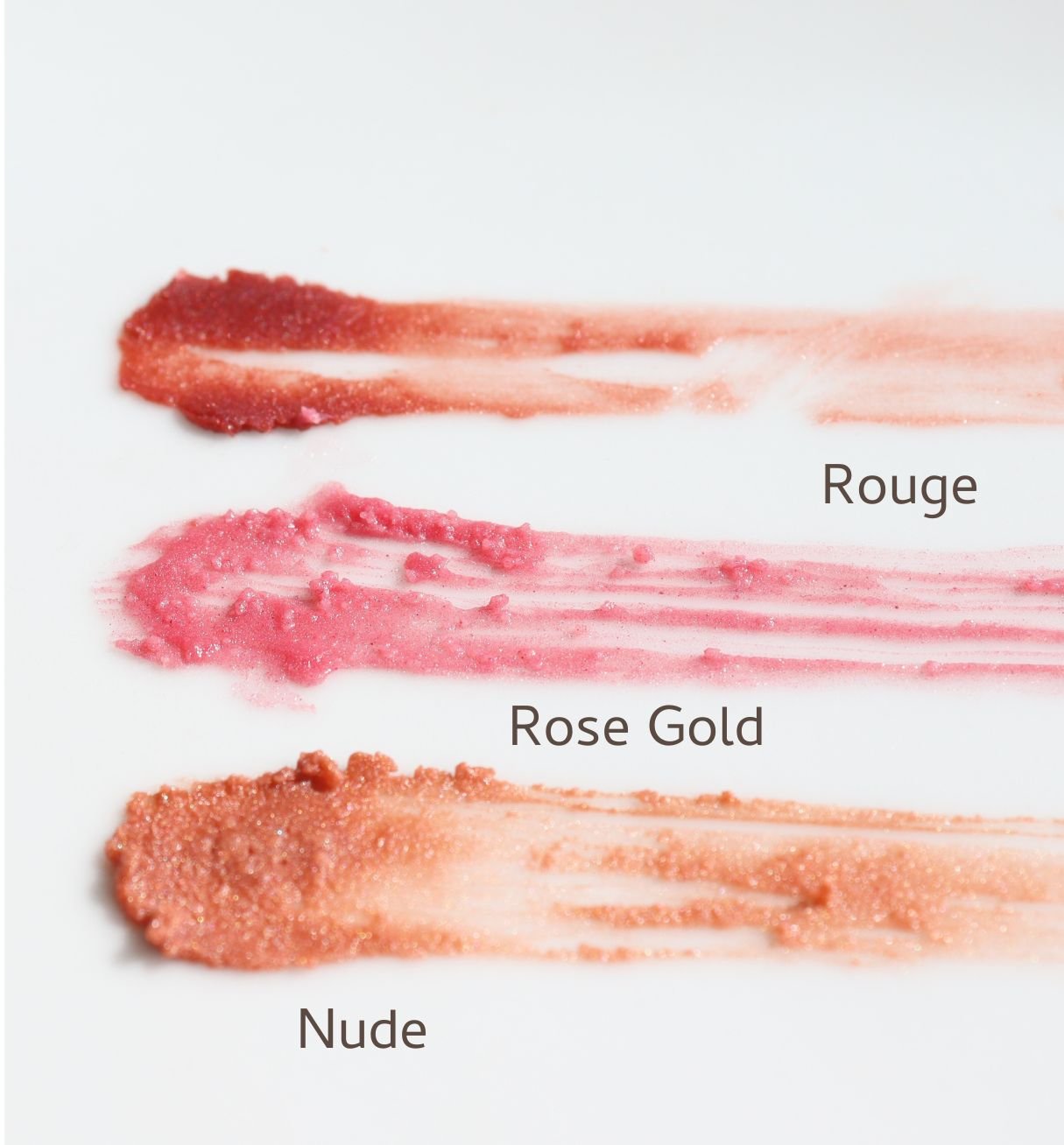 Three swatches of tinted lip balm labeled 'Rouge', 'Rose Gold', and 'Nude' on a white background.