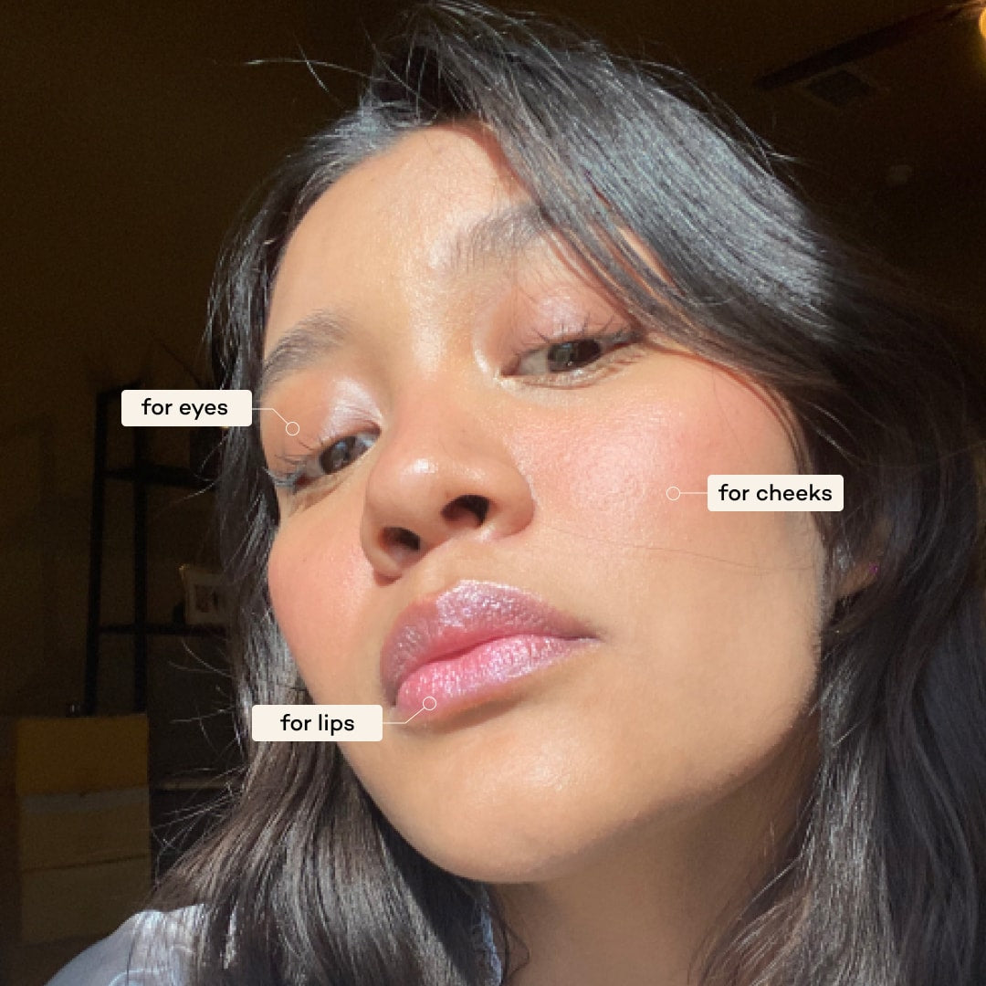 Close-up of a person applying makeup to their face with labels for eyes, cheeks, and lips.