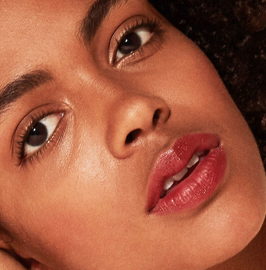 Close-up of a woman's face wearing makeup with a soft focus on her eyes and lips.