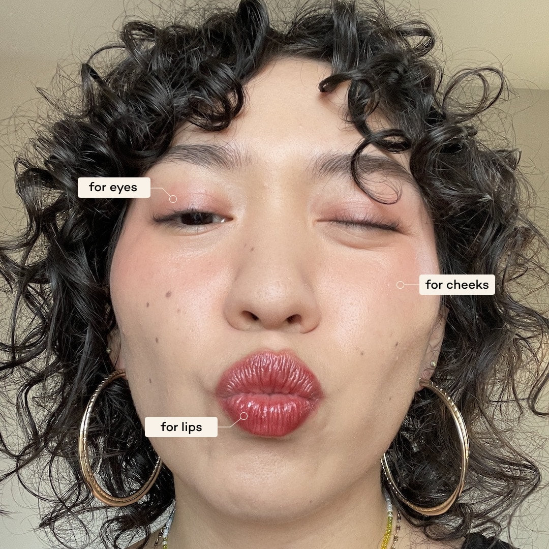 Close-up of a person wearing makeup with labeled makeup application points on their face.