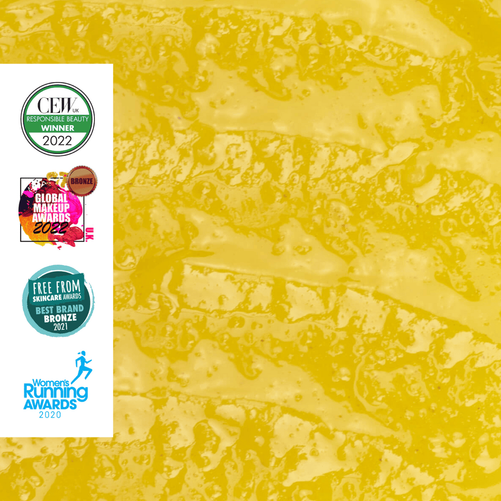 Closeup of cleansing balm texture with multiple awards logos on the left side.