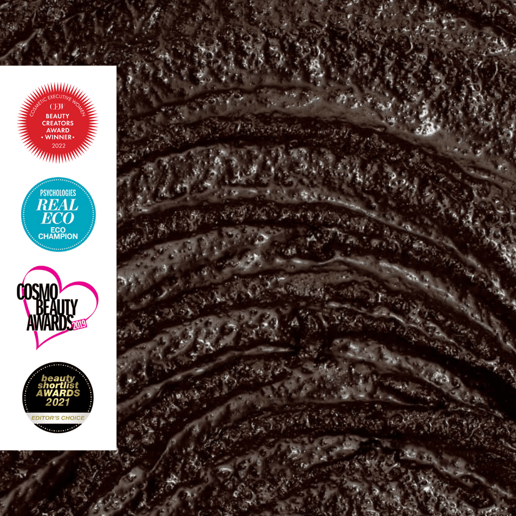 Close-up of body scrub texture with awards logos on the left.