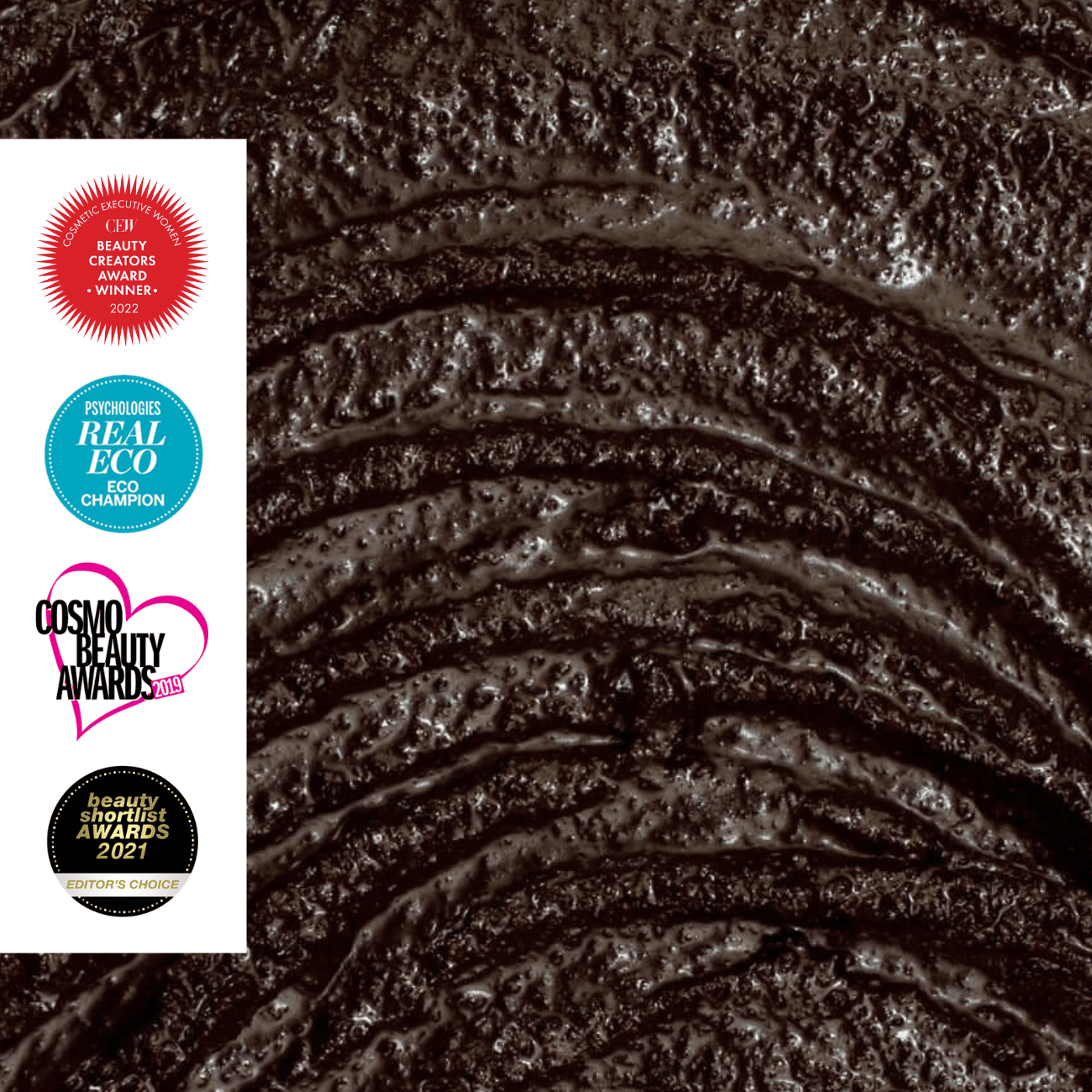 Close-up of body scrub texture with awards logos on the left.