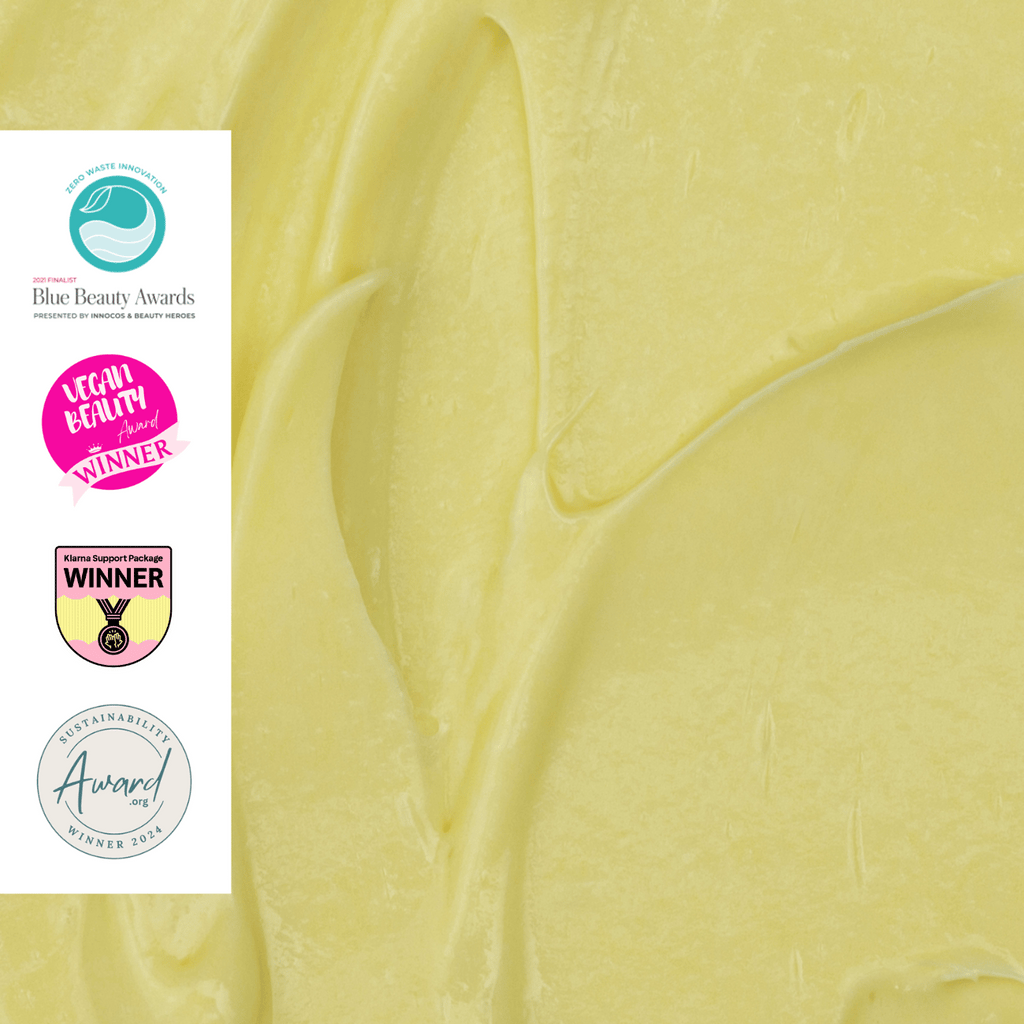 Close-up of smooth yellow cream with Blue Beauty Awards and other awards logos on the left.